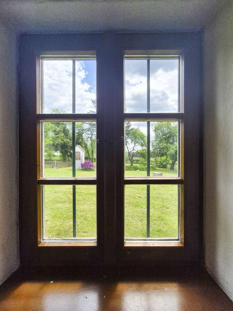 Fensterblick auf den grünen Garten und die ländliche Umgebung.