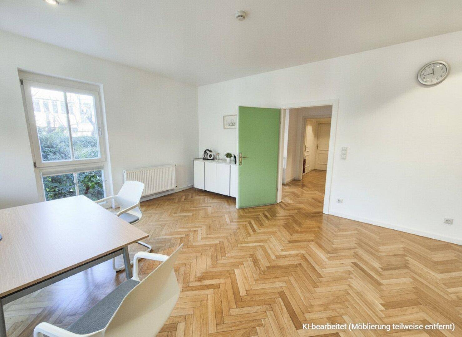 Freundlicher Raum mit Fischgrätparkett, einem großen Fenster und einer auffälligen grünen Tür.