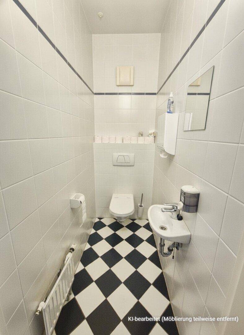 Kleines Gäste-WC mit schwarz-weiß karierten Fliesen, wandhängendem WC und kleinem Waschbecken.