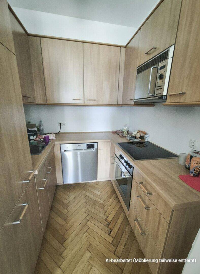 Funktionale Küche mit hellen Holzschränken, Fischgrätparkett und modernen Einbaugeräten.