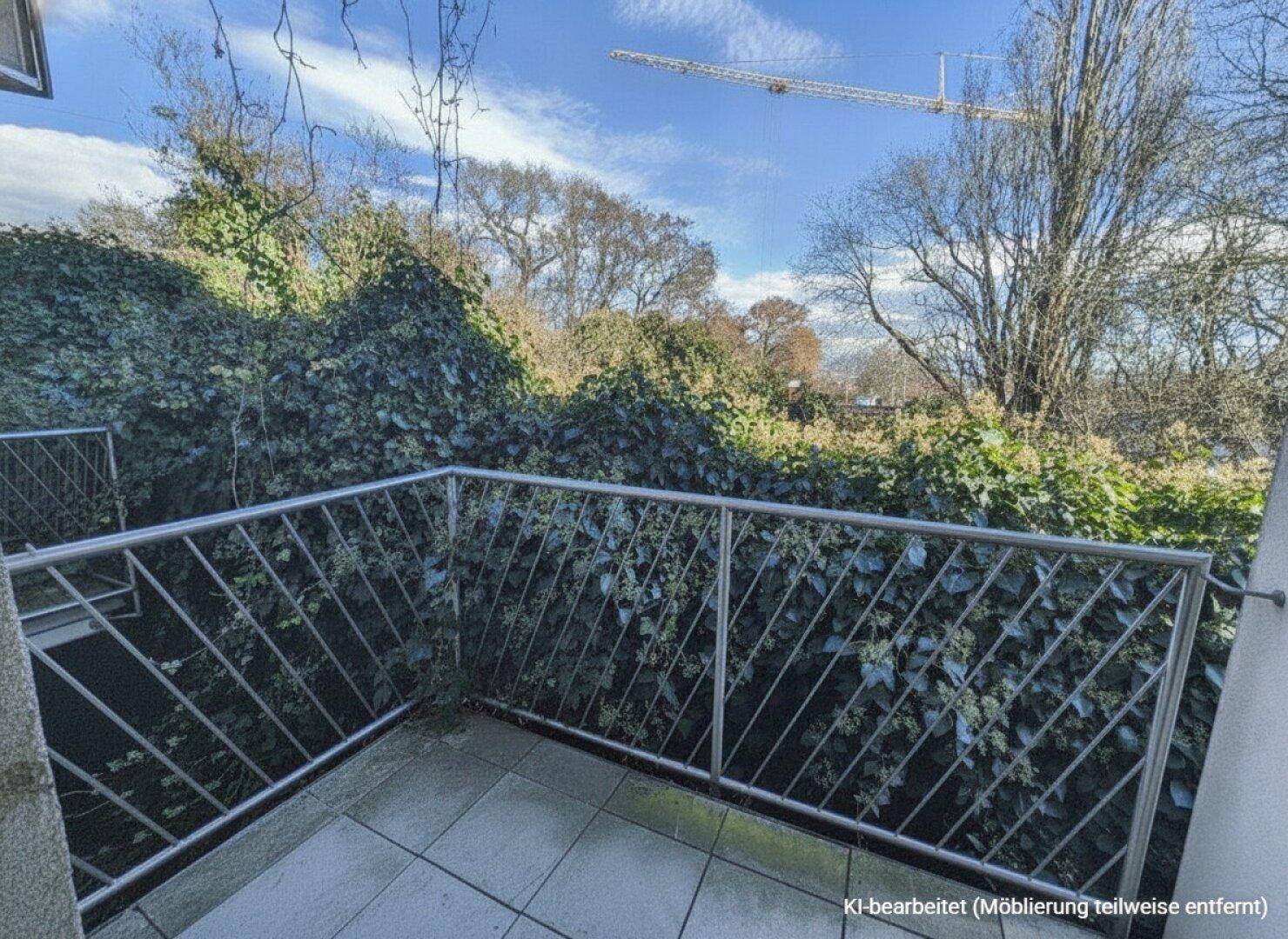 Balkon mit Fliesenboden und Blick ins Grüne, im Hintergrund ist ein Baukran zu sehen.