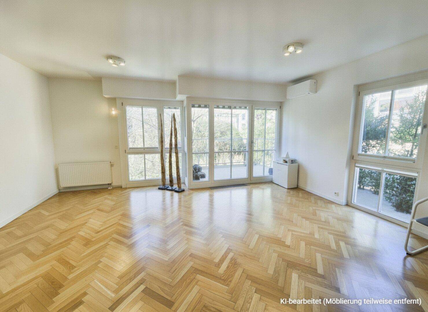Helles Wohnzimmer mit Fischgrätparkett, großen Fenstern und Zugang zu einem Balkon.
