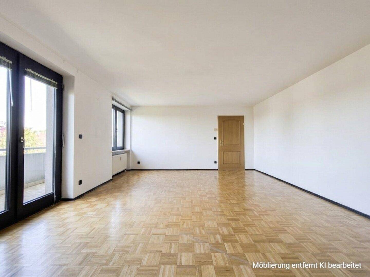 Helles, leeres Wohnzimmer mit Parkettboden und Zugang zu einem Balkon.