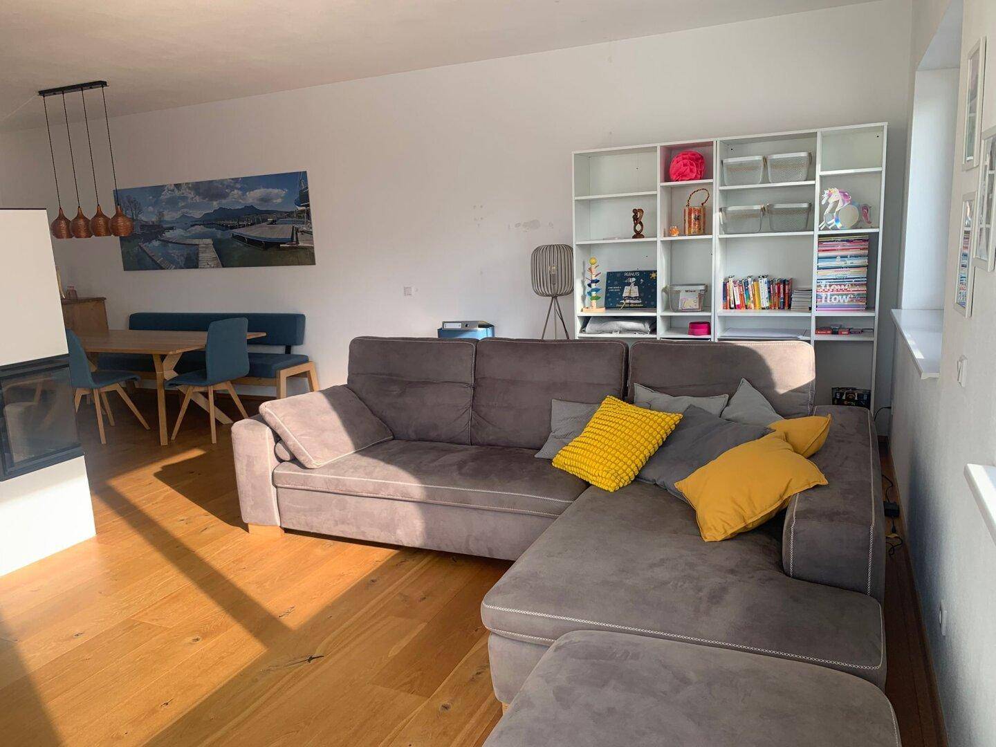 Heller offener Wohn- und Essbereich mit gemütlichem Sofa, Kamin und Holzboden.