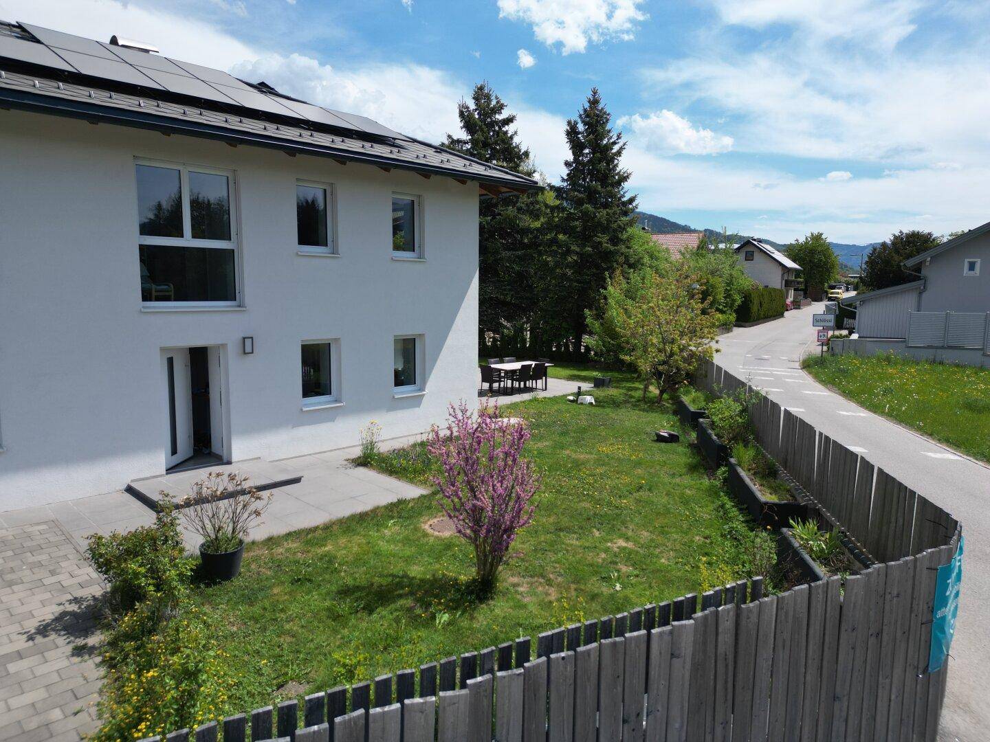 Modernes Einfamilienhaus mit Photovoltaikanlage, Garten und Sitzbereich im Grünen.