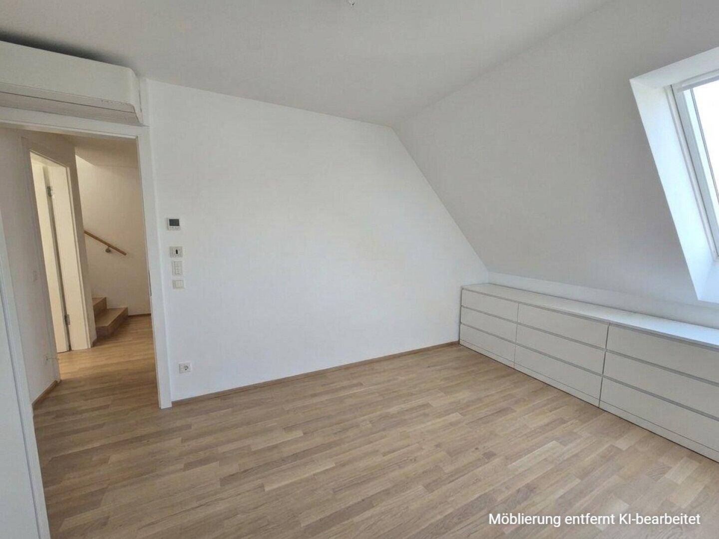 Schlafzimmer mit Dachschräge, Parkettboden und integrierten Schubladen unter dem Fenster.