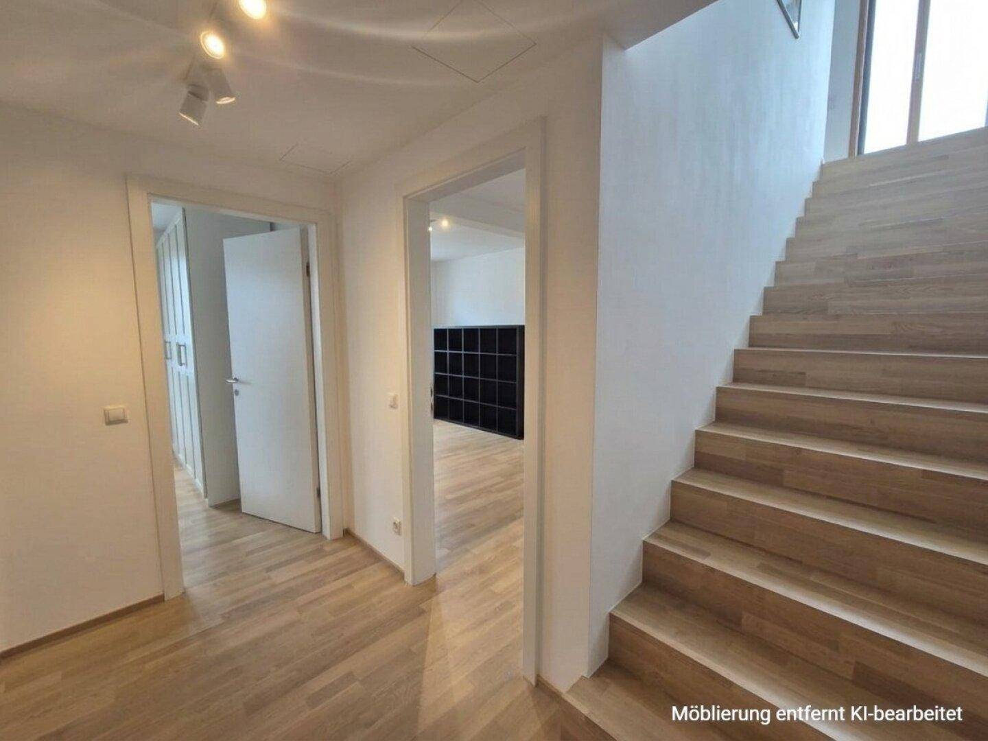 Heller Flur mit Holztreppe und Zugang zu weiteren Räumen im Obergeschoss.