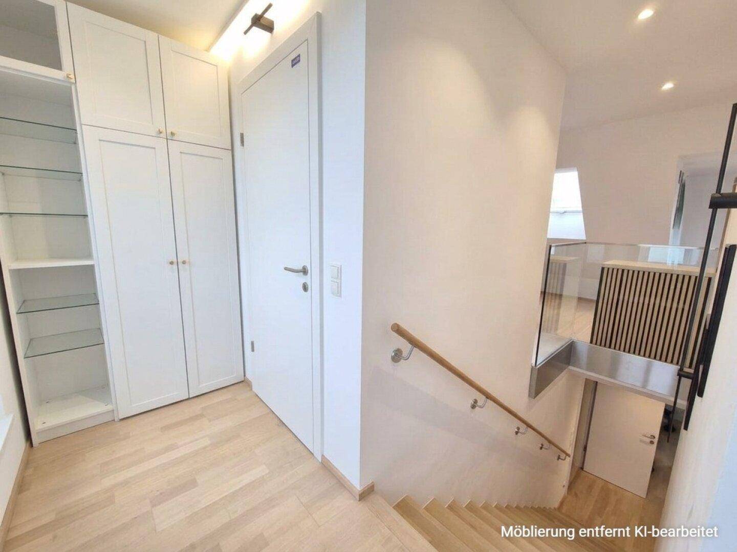 Eingangsbereich mit Einbauschränken, hellem Holzboden und Treppenaufgang.