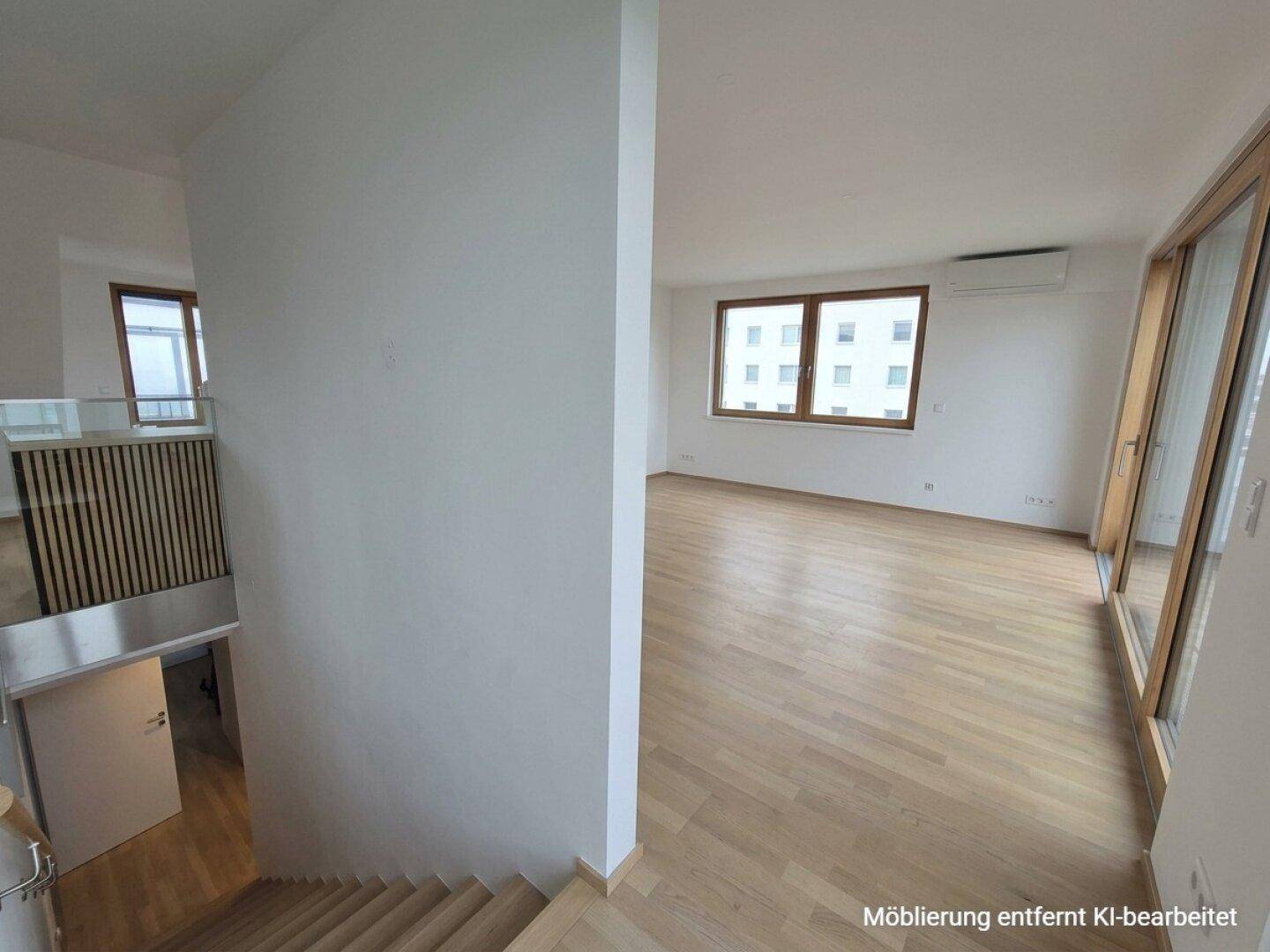 Blick vom Treppenbereich in ein helles Wohnzimmer mit Parkettboden und großen Fenstern.