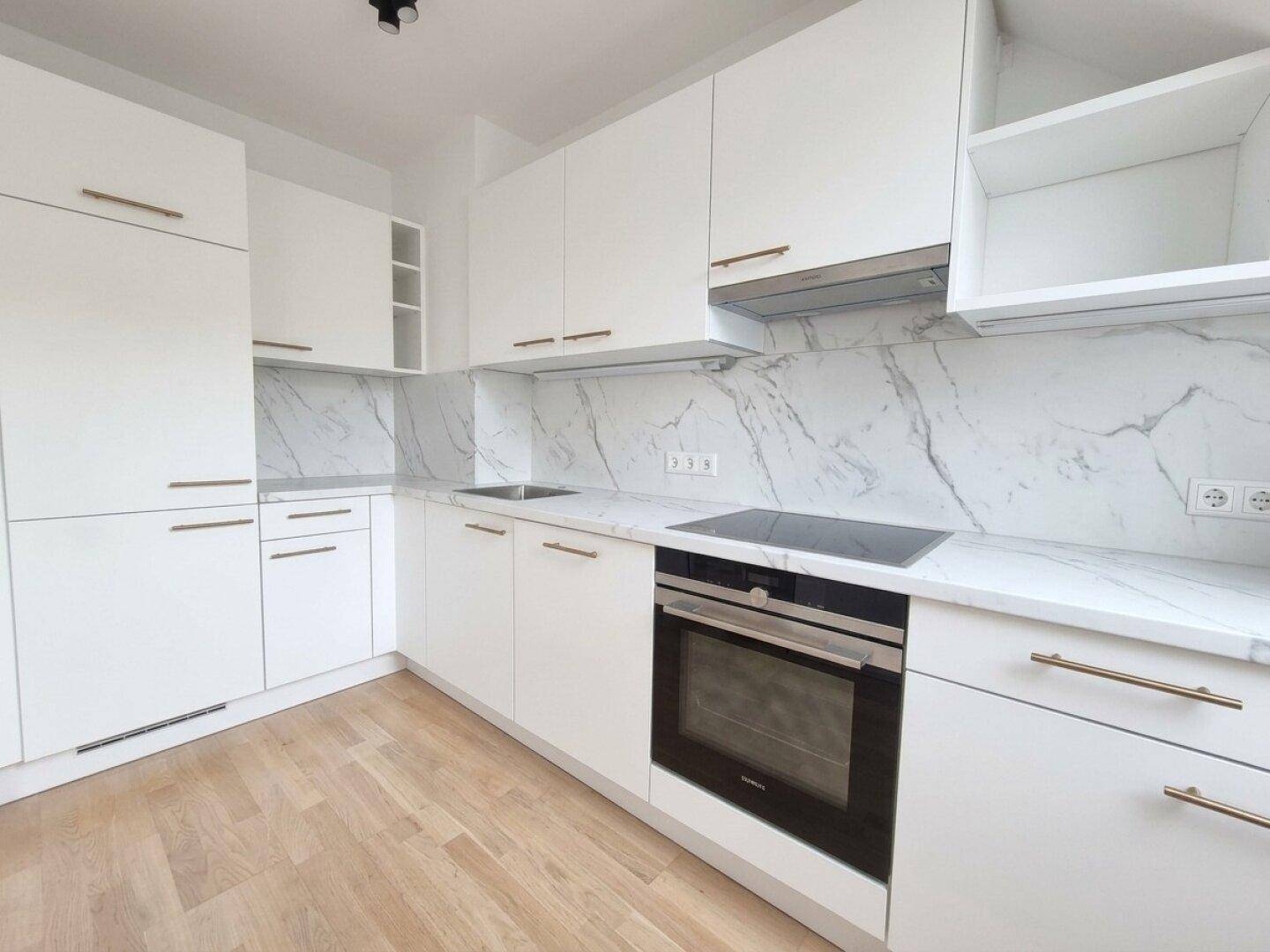 Moderne Einbauküche mit weißen Fronten, Marmoroptik-Arbeitsplatten und integrierten Geräten.