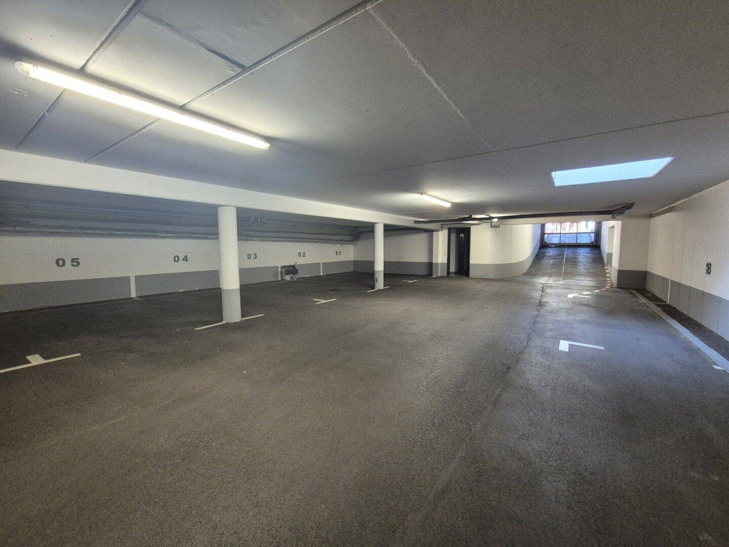 Geräumige Tiefgarage mit markierten Stellplätzen und heller Beleuchtung.