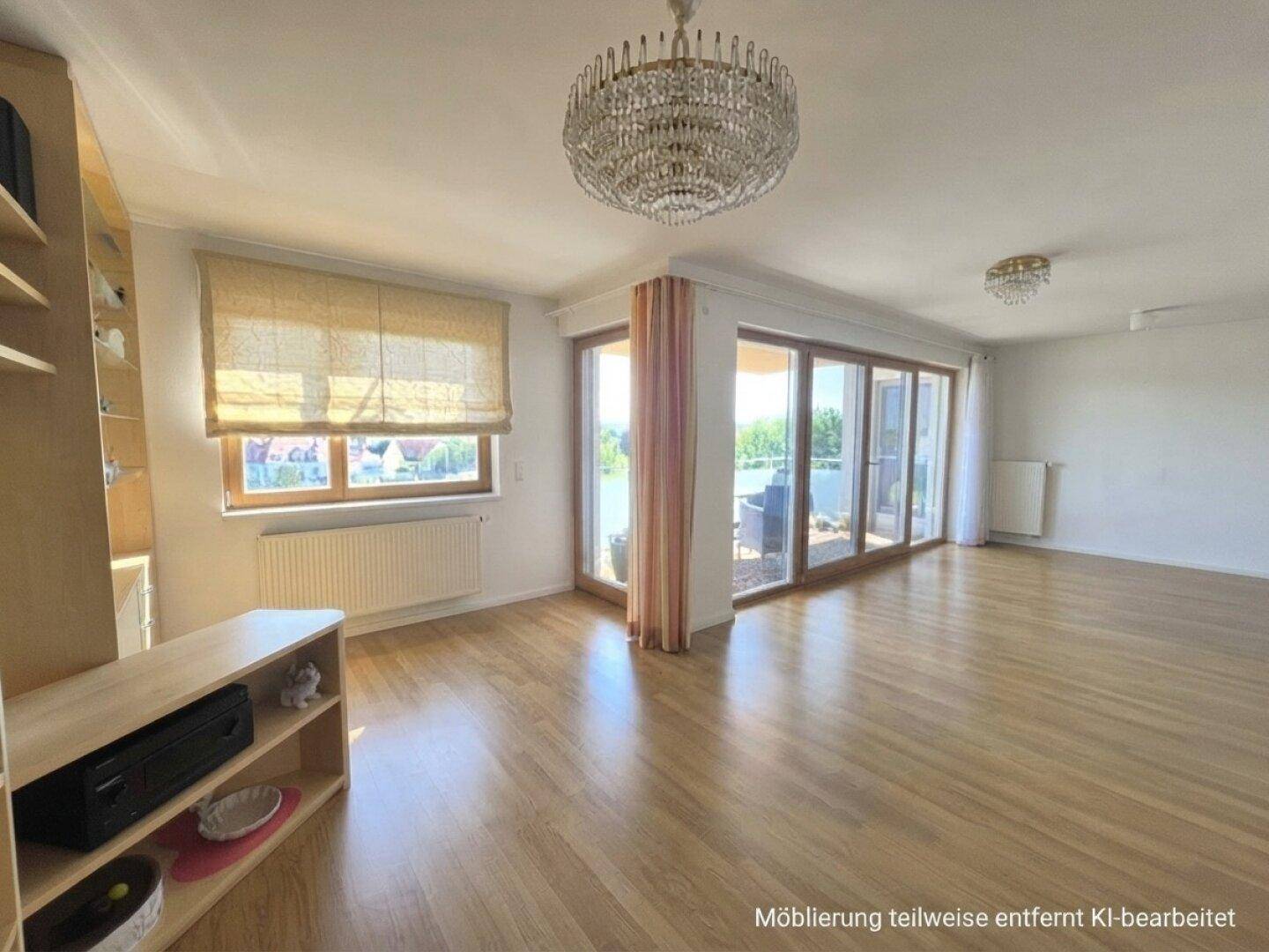 Geräumiges Wohnzimmer mit Laminatboden, Kronleuchter und großzügigem Balkonzugang.