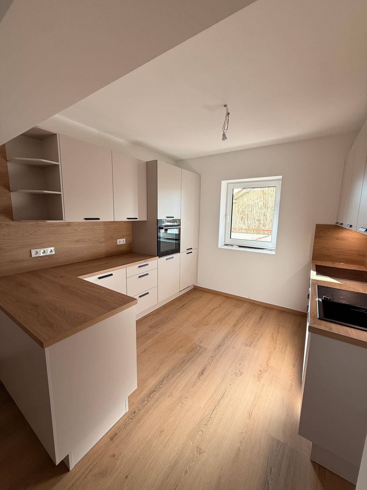 Helle Einbauküche mit modernen Geräten, Holzoptik-Arbeitsplatten und viel Stauraum.