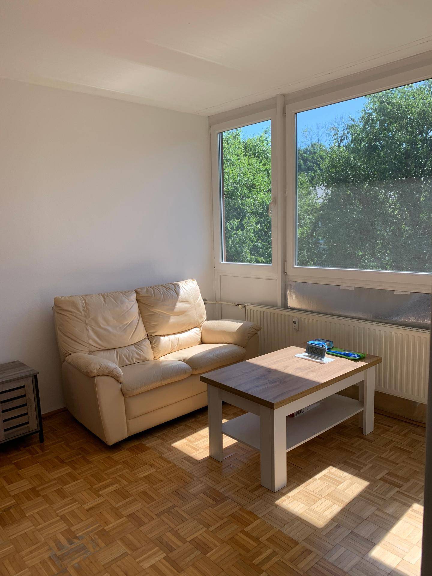 Gemütliches Wohnzimmer mit beigem Sofa, Couchtisch und Blick ins Grüne.