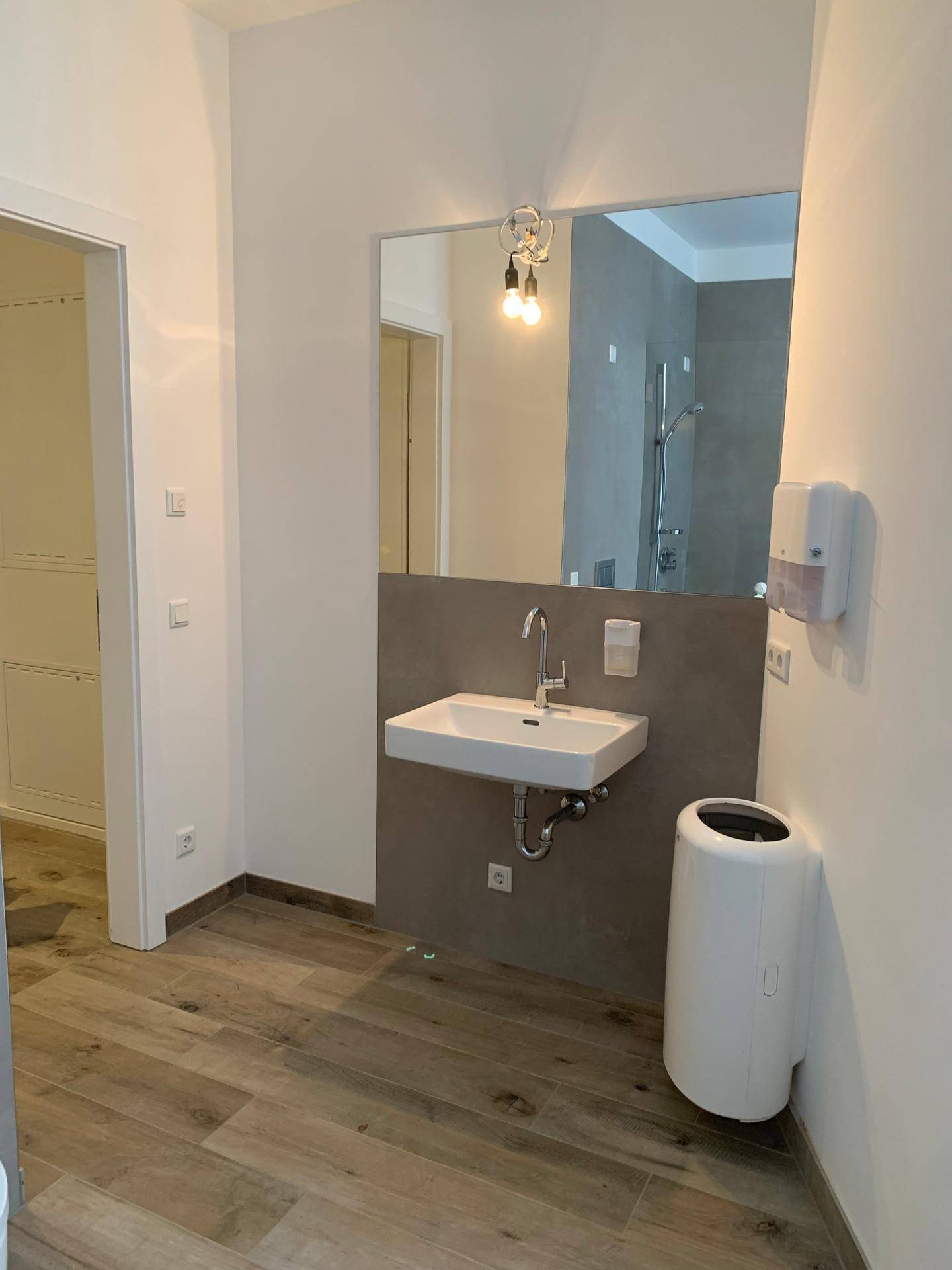 Geräumiges Badezimmer mit Waschbecken, großem Spiegel und Holzboden.