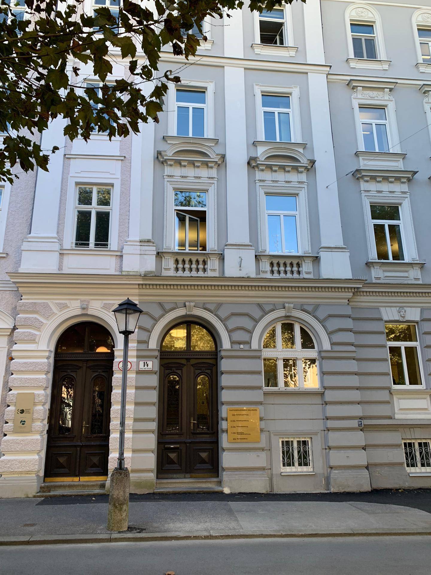 Detailansicht der eleganten Fassade eines Altbaus mit verzierten Fenstern und Holztüren.