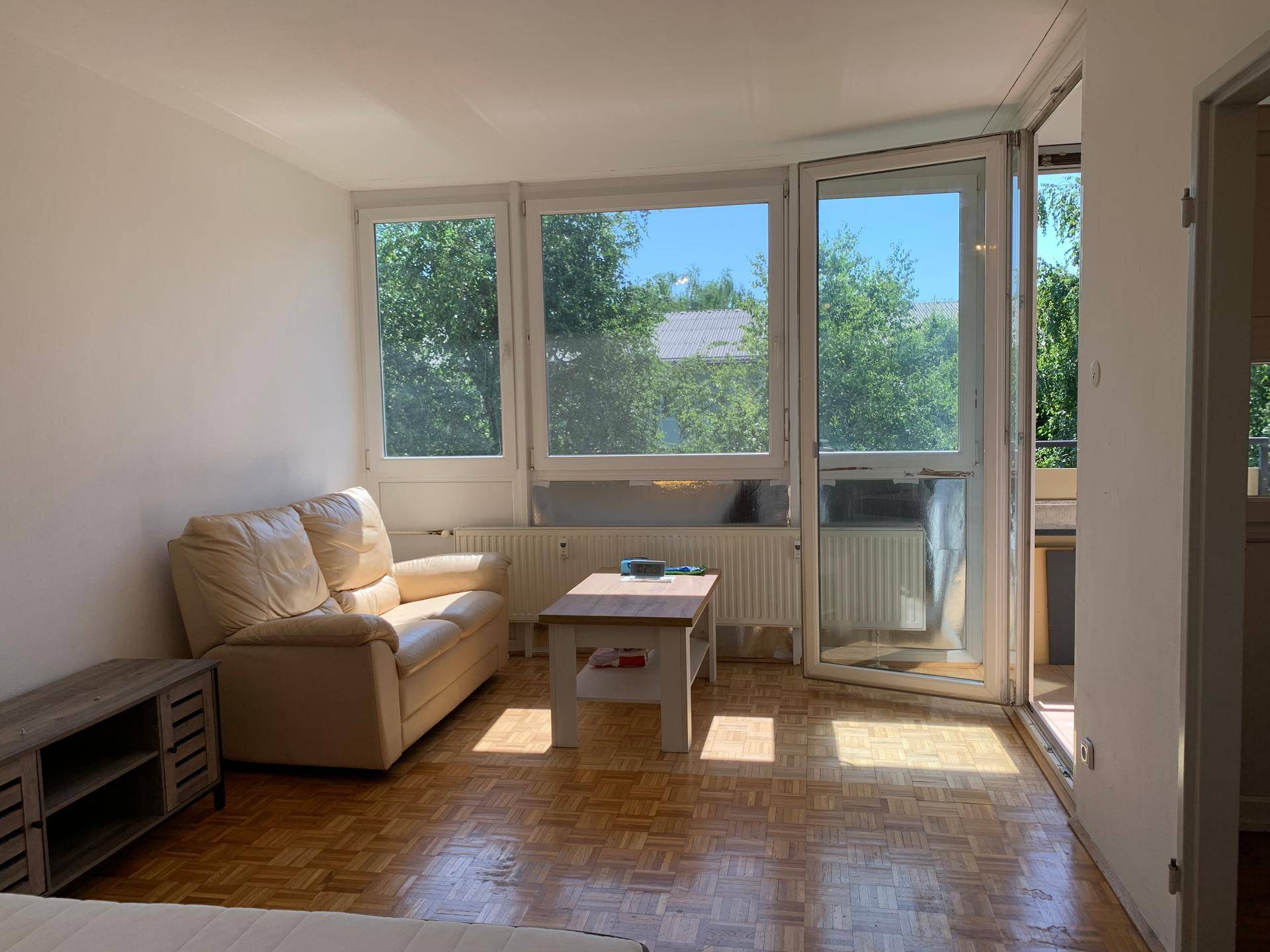 Geräumiges Wohnzimmer mit Parkettboden, großen Fenstern und viel Tageslicht.