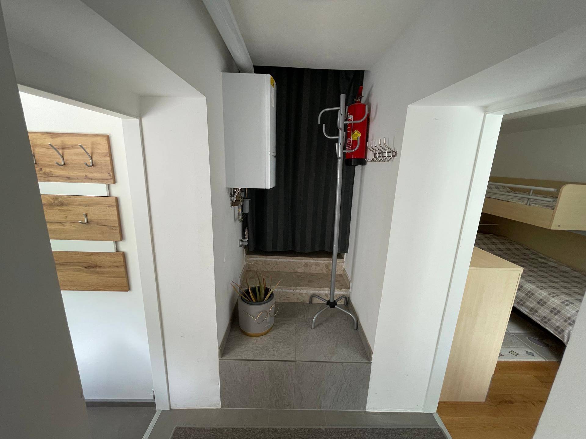 Eingangsbereich mit Garderobe, Feuerlöscher und Treppe zu einem weiteren Bereich.