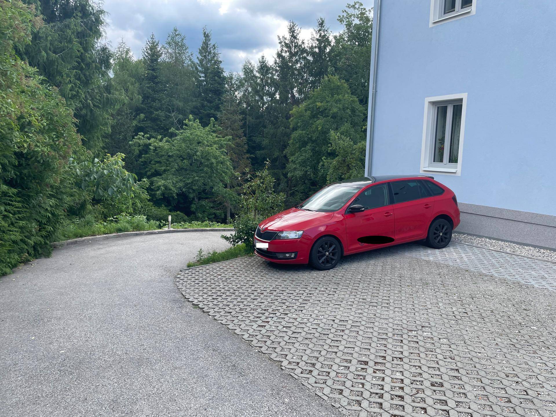 Außenansicht des Gebäudes mit gepflastertem Parkplatz und umgebender Natur.
