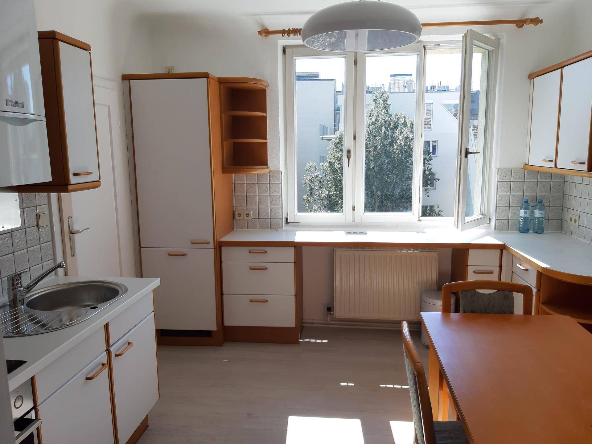 Geräumige Küche mit Essbereich, Einbauschränken und großem Fenster mit Blick ins Grüne.