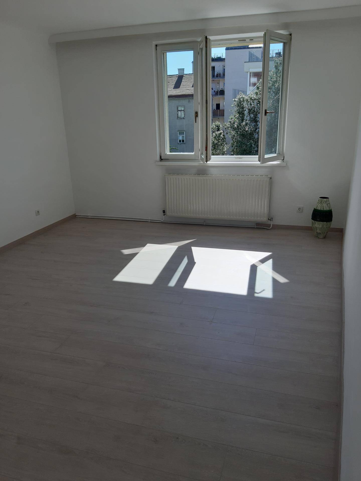 Helles, leeres Zimmer mit großen Fenstern und hellem Laminatboden, ideal für Schlafzimmer oder Wohnzimmer.