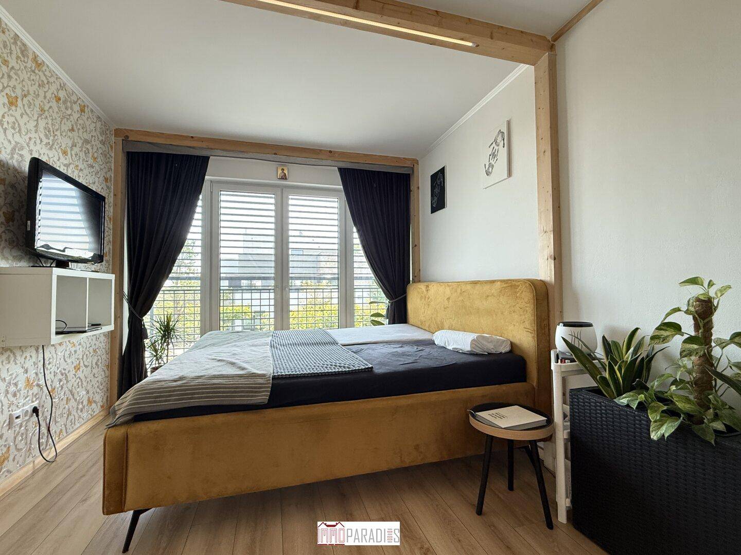 Gemütliches Schlafzimmer mit Doppelbett, Holzboden und Zugang zu einem Balkon.