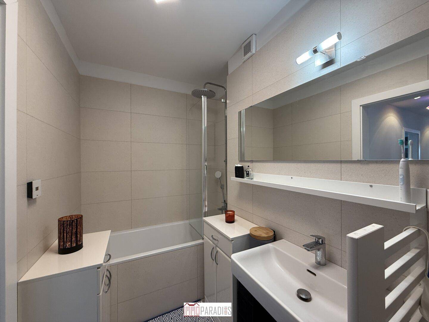 Modernes Badezimmer mit Badewanne, Dusche, Einzelwaschbecken und hellen Fliesen.