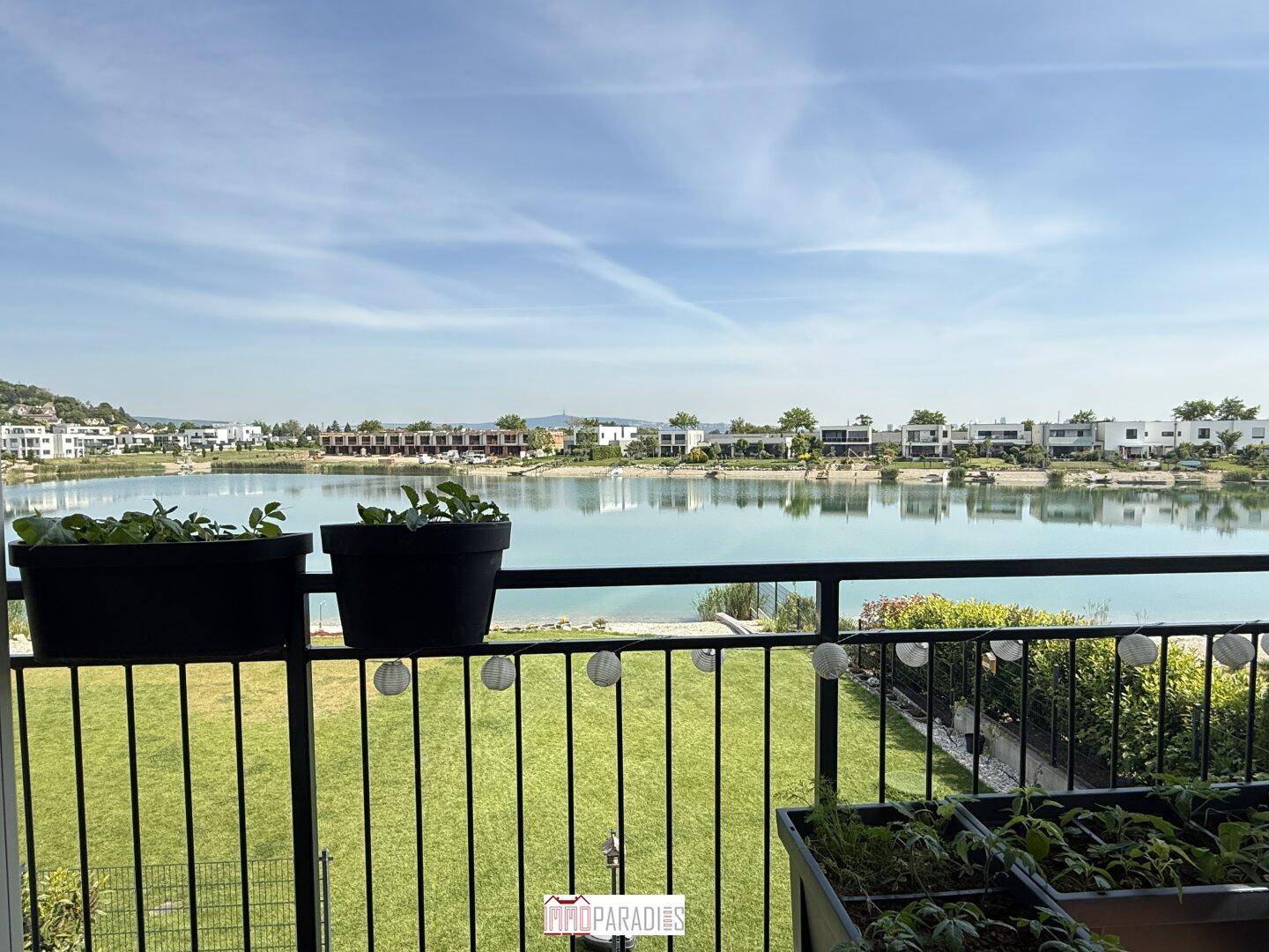 Balkon mit weitem Seeblick, Pflanzen und dekorativer Beleuchtung.