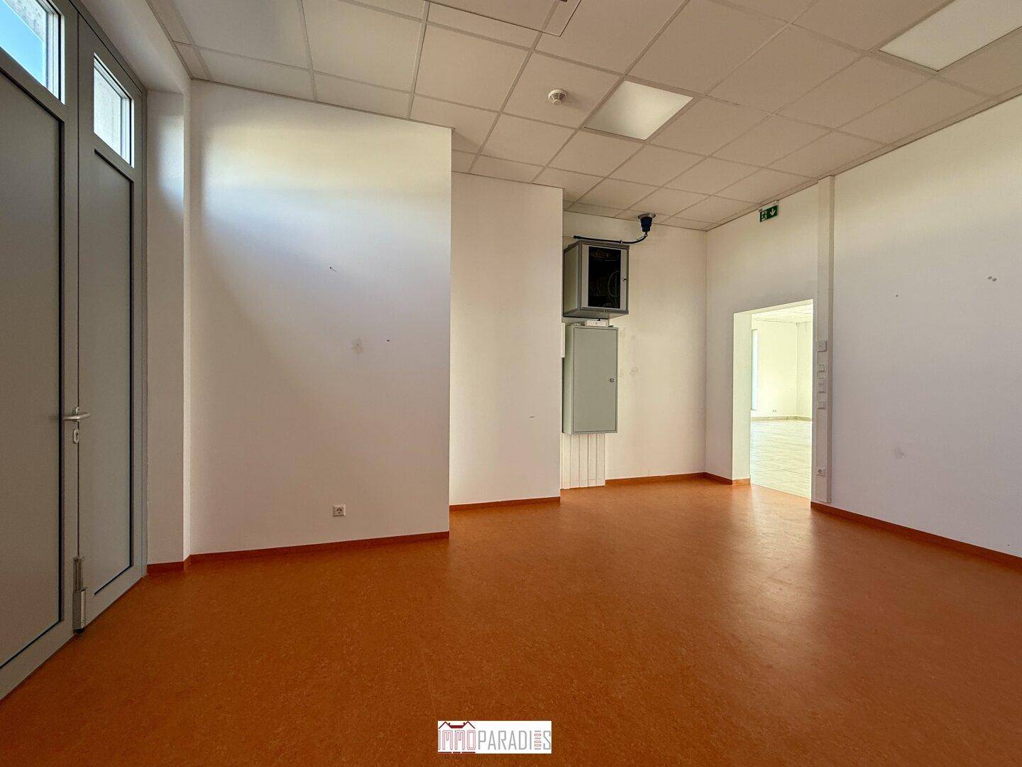 Heller Büroraum mit orangefarbenem Linoleumboden und weißen Wänden, bereit zur individuellen Gestaltung.