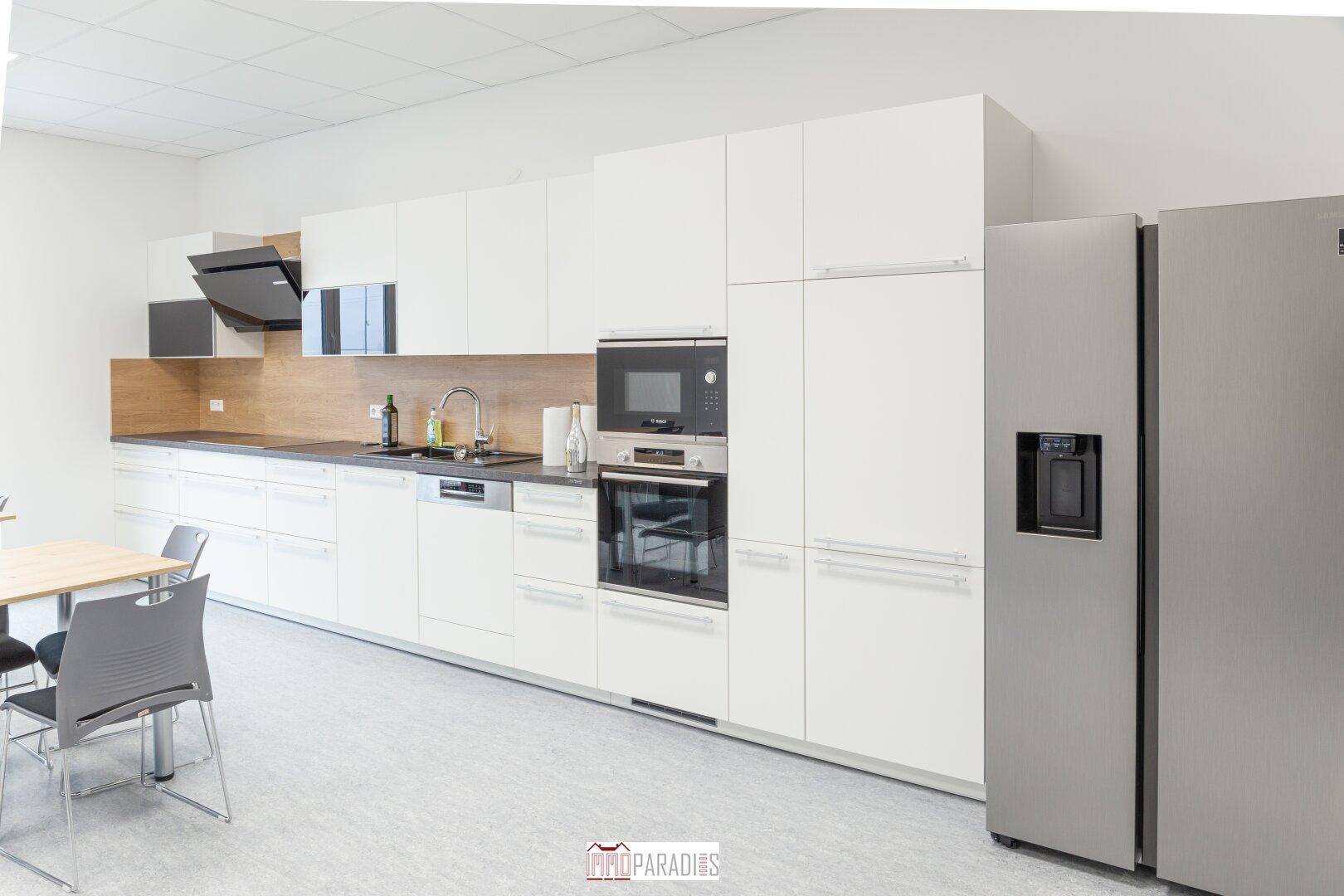 Detailansicht der modernen Einbauküche mit weißen Fronten, integrierten Geräten und großem Kühlschrank.