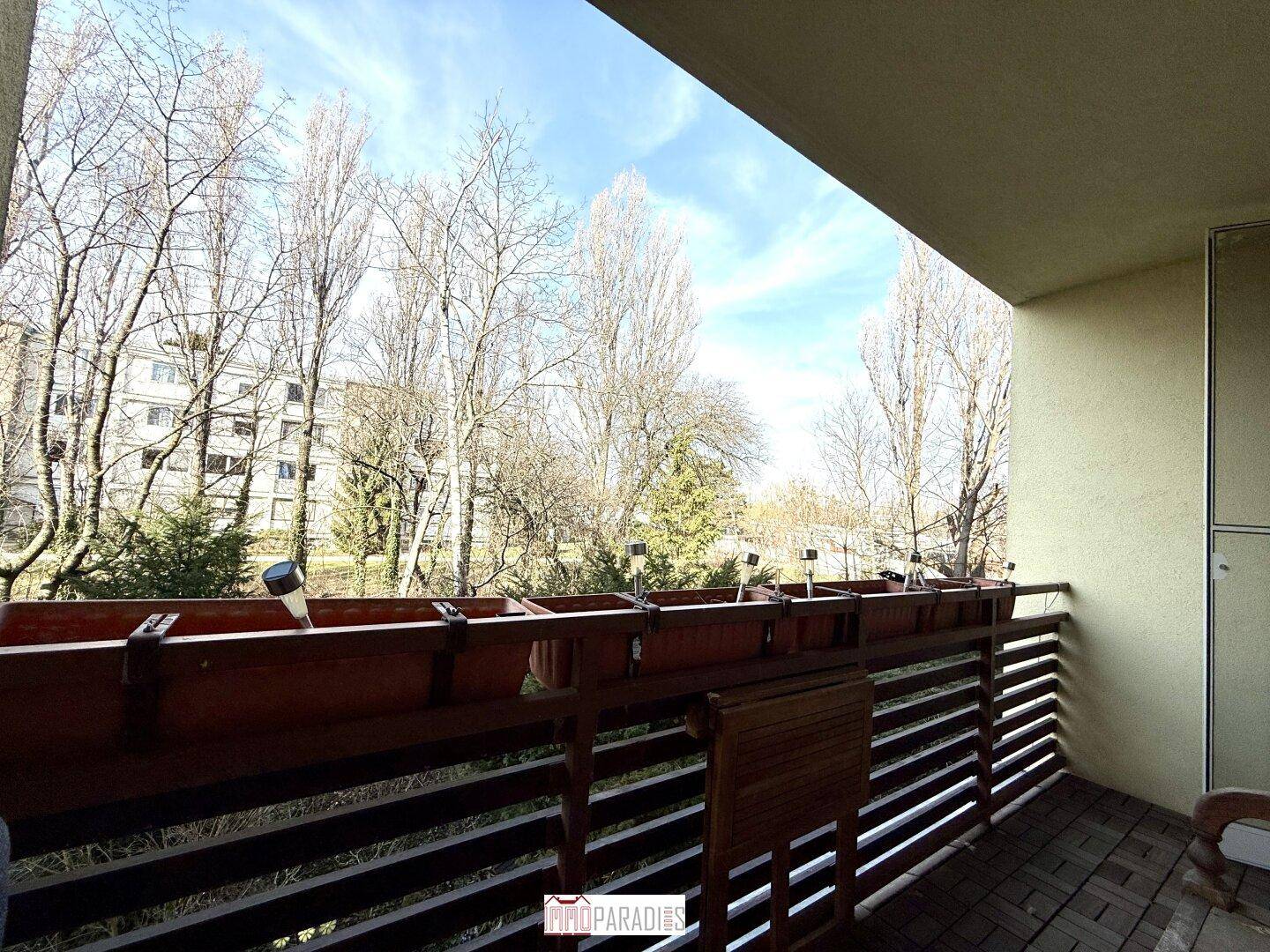 Balkon mit Holzboden und weitem Blick auf Bäume und die Umgebung.
