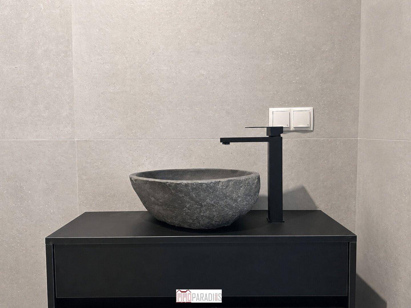 Detailaufnahme eines modernen Badezimmers mit Steinschale und schwarzer Armatur.