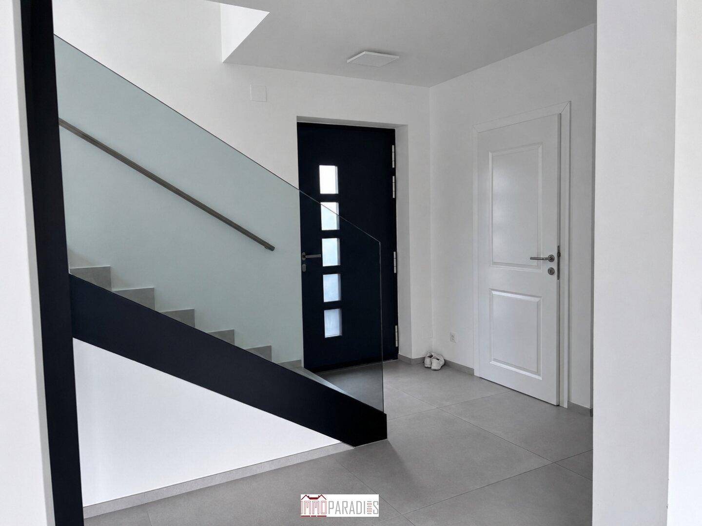 Eingangsbereich mit moderner Treppe, Fliesenboden und zwei Türen.