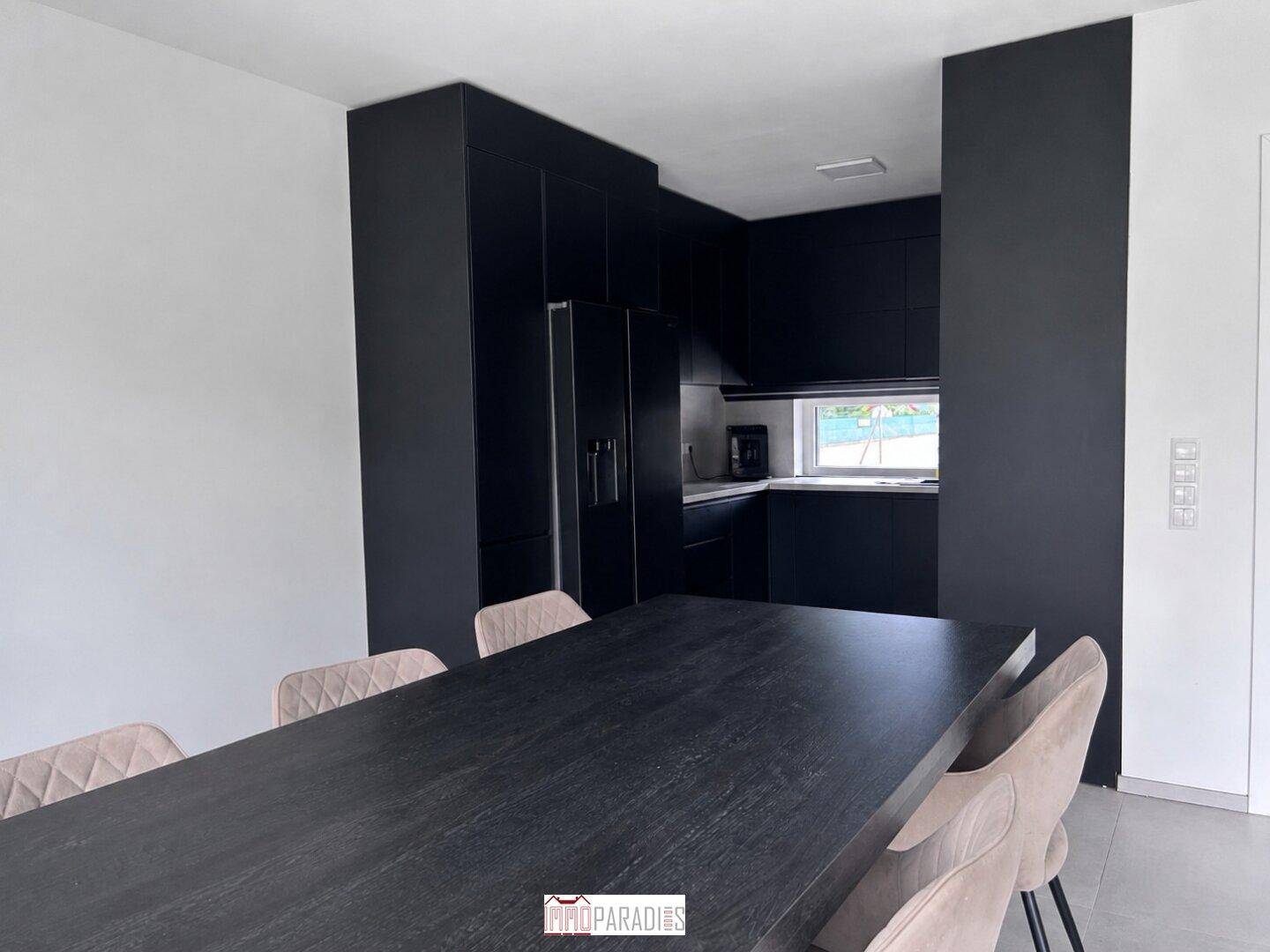 Moderne Küche mit dunklen Einbauschränken, Kühlschrank und Fenster.