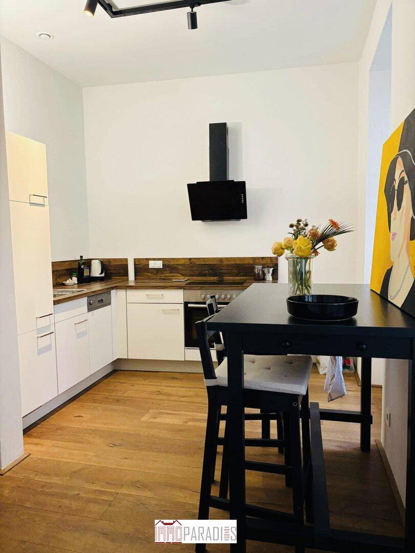 Moderne Küche mit weißen Schränken, Holzarbeitsplatten und einem Essbereich mit Bartisch.