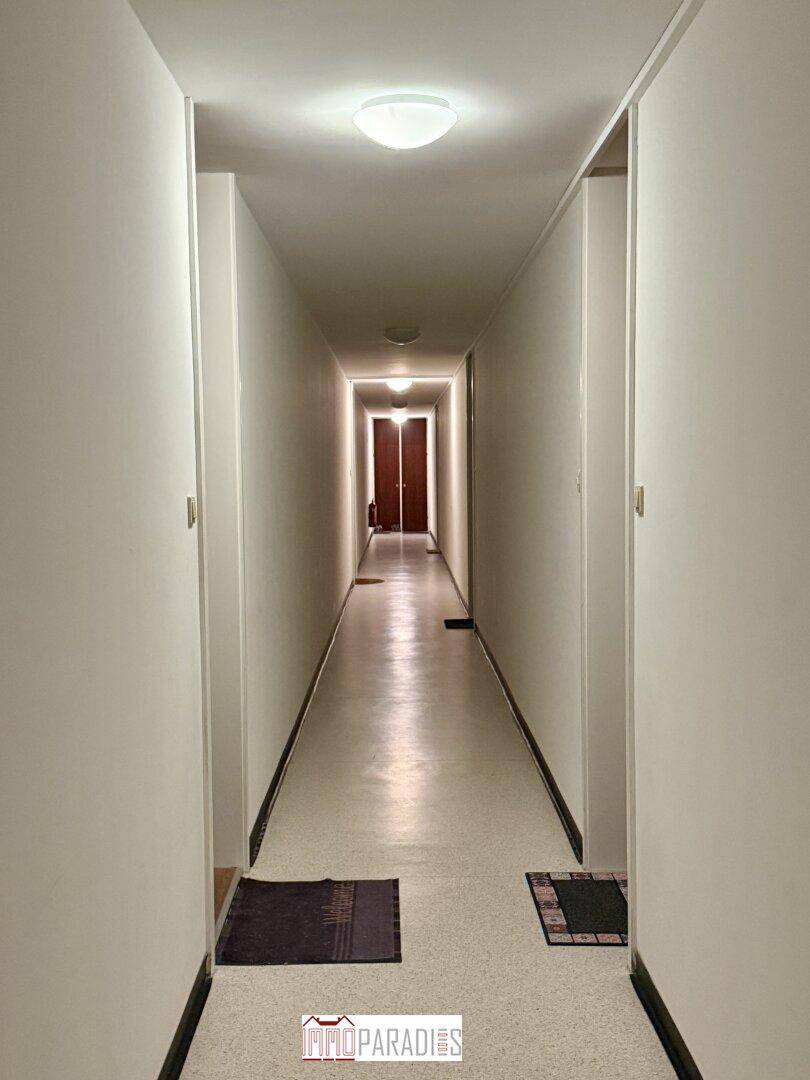 Langer, heller Flur mit schlichtem Design, der die verschiedenen Bereiche der Wohnung verbindet.
