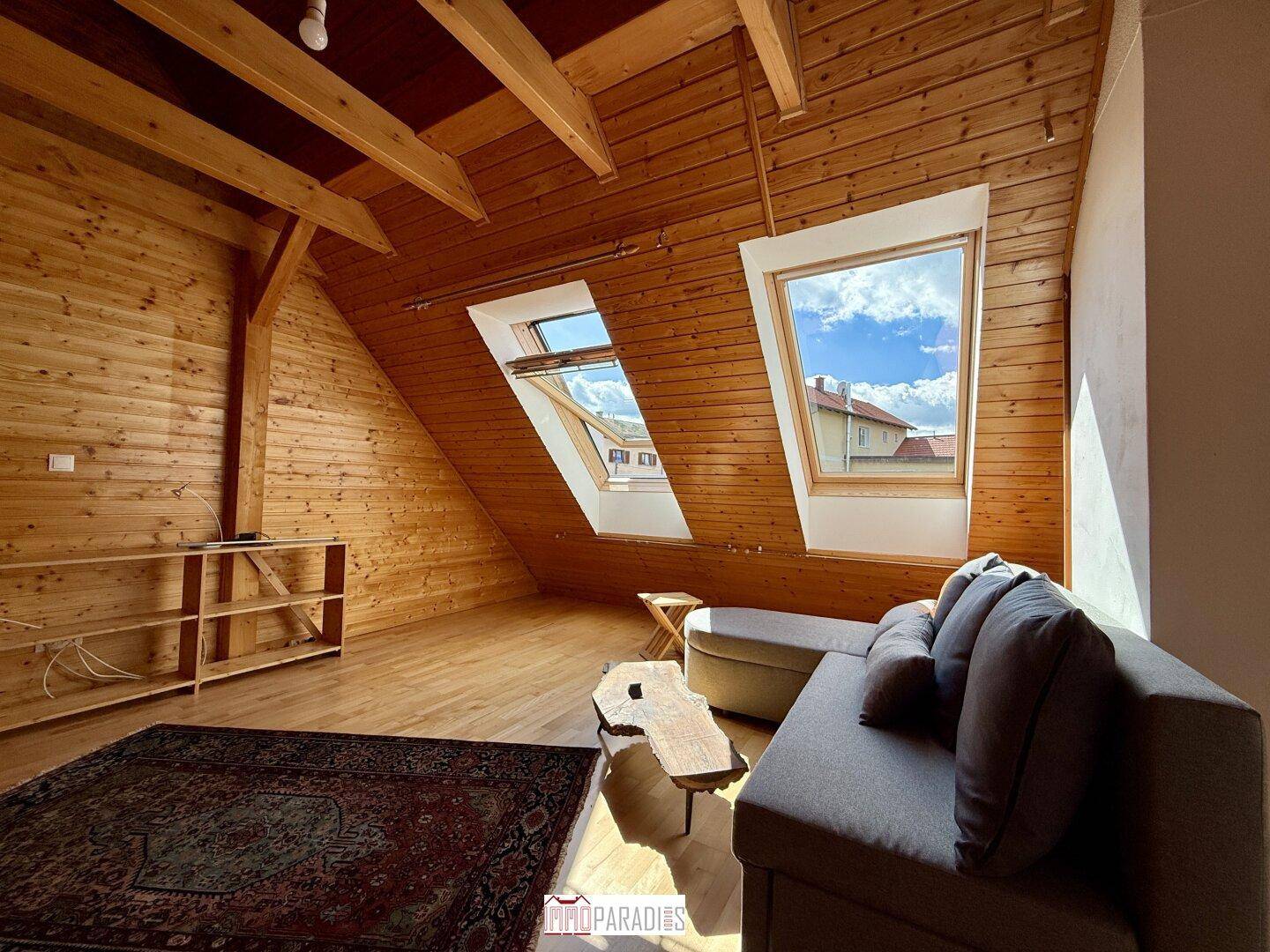 Ausgebauter Dachboden mit Holzwänden, Dachfenstern und einem Sofa, ideal als zusätzlicher Wohnraum.