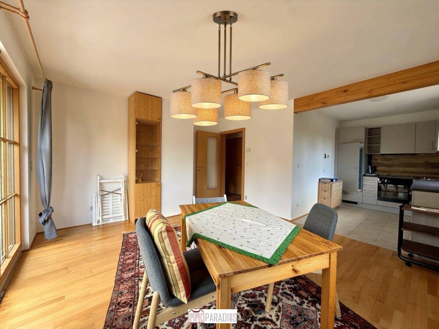 Gemütlicher Essbereich mit Holztisch, Pendelleuchte und offenem Übergang zur Küche.