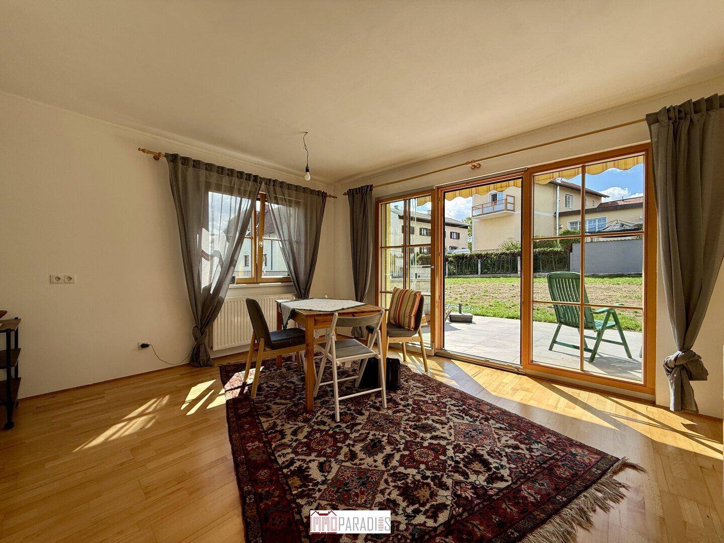 Essbereich mit Holzboden, Teppich und Zugang zur Terrasse durch große Schiebetüren.