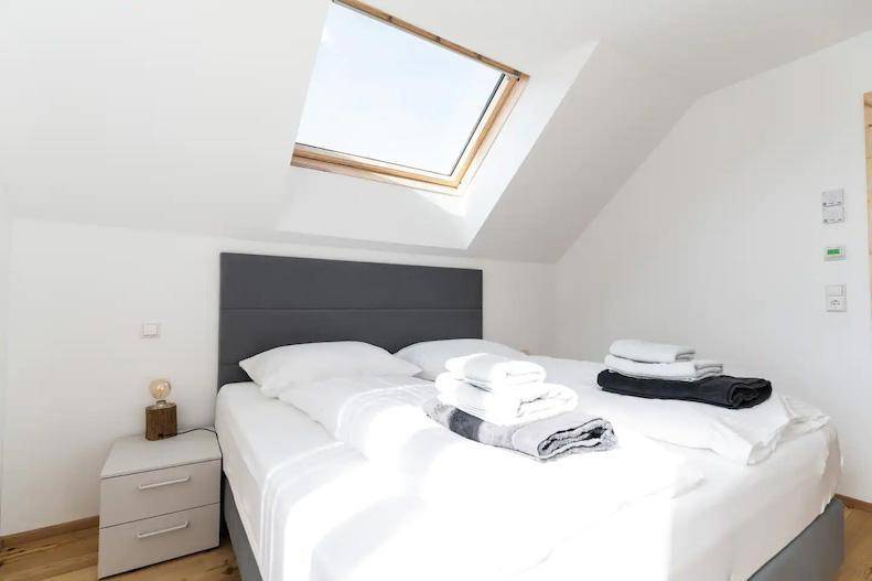 Dachgeschoss-Schlafzimmer mit Dachfenster, Doppelbett und Holzboden.