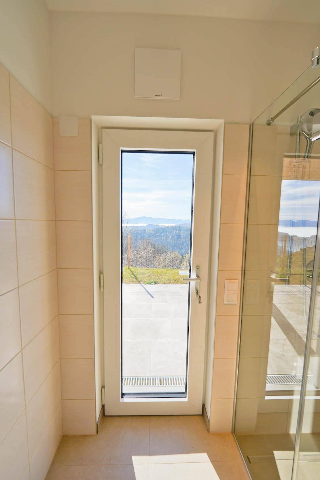 Badezimmertür mit Glasausschnitt und Blick auf die umliegende Landschaft.