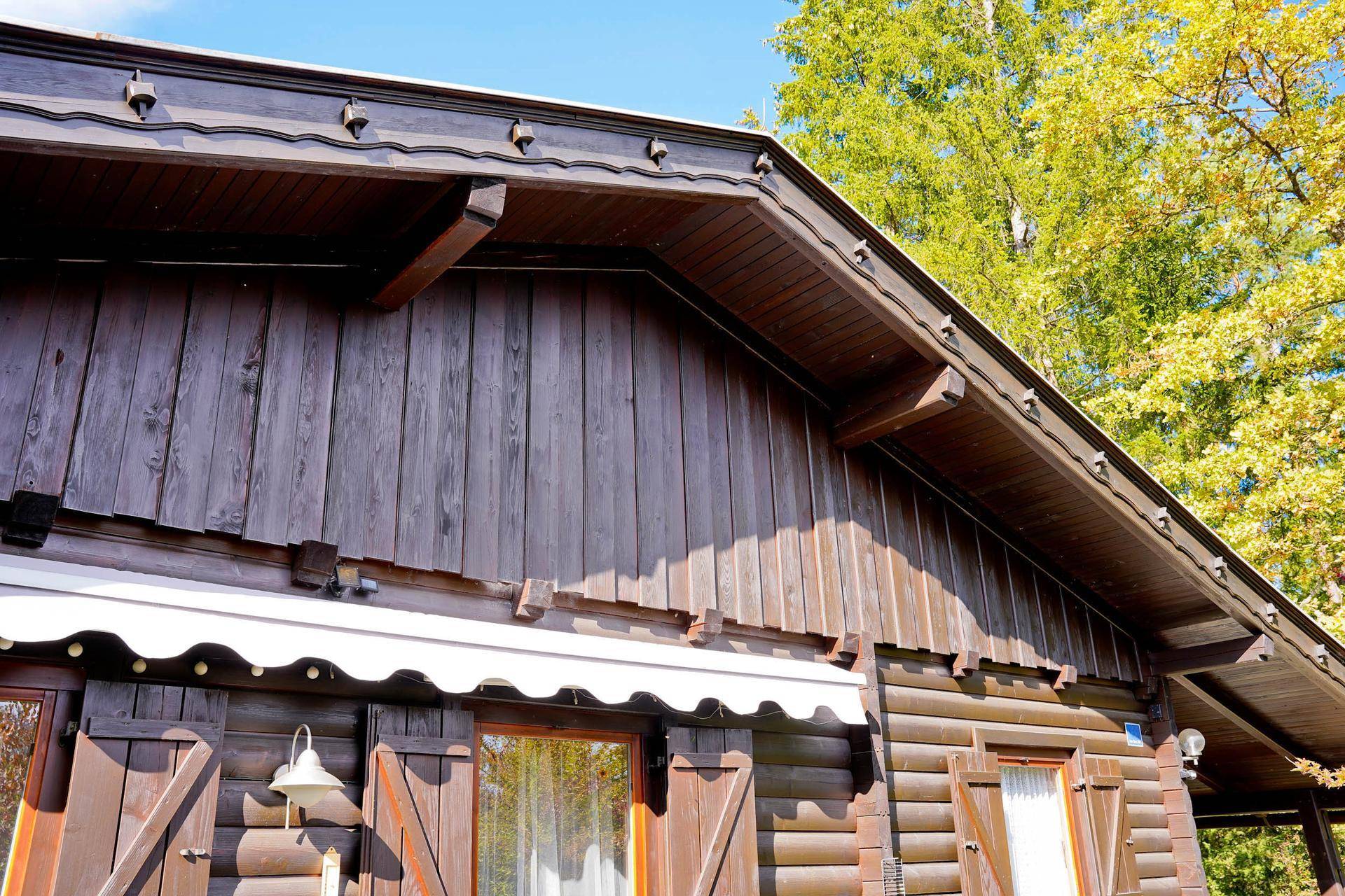 Detailansicht des Giebels des Holzchalets mit aufwendiger Holzverkleidung und Dachüberstand.