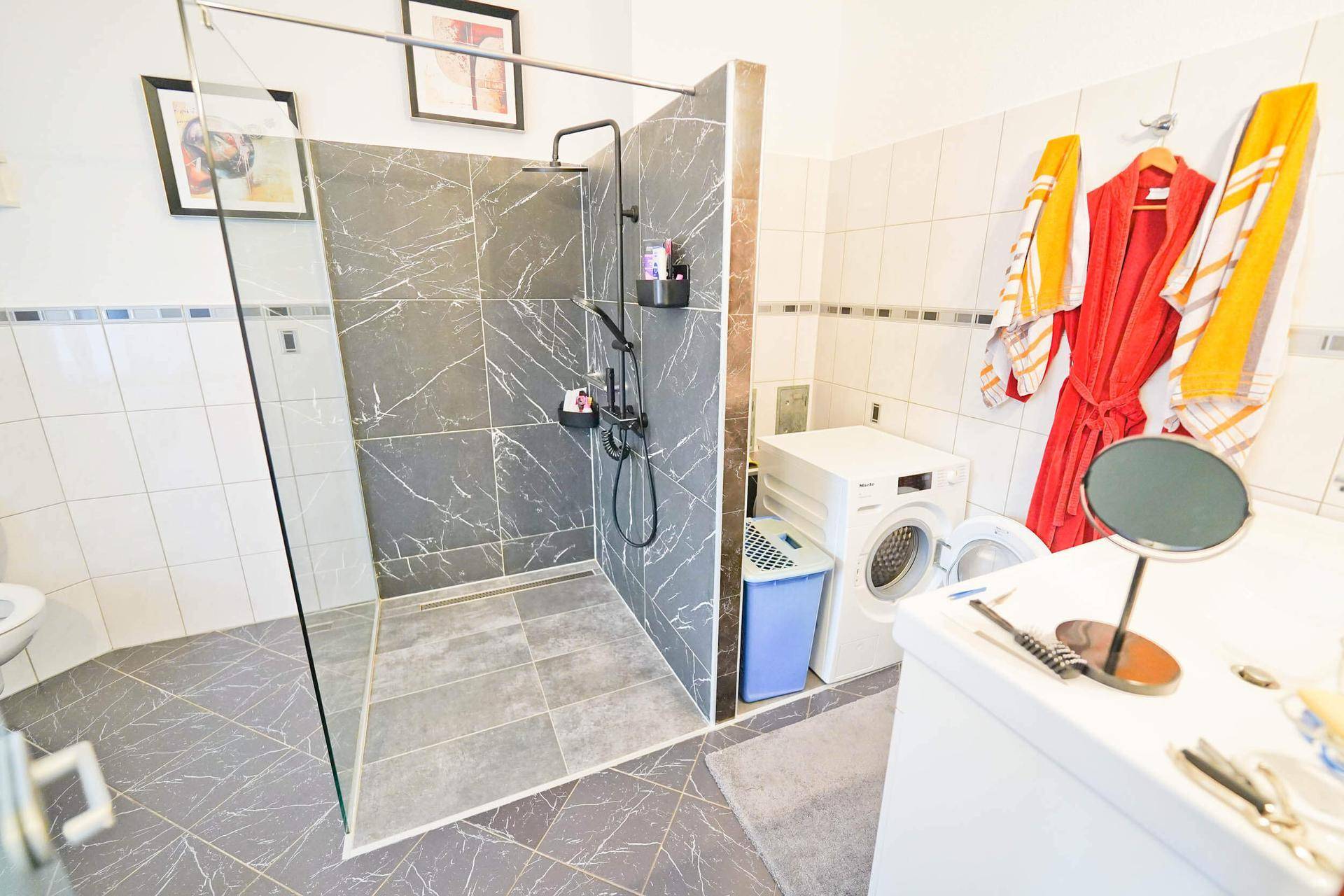 Modernes Badezimmer mit begehbarer Dusche, Waschmaschine und Trockner sowie einem Waschbecken.