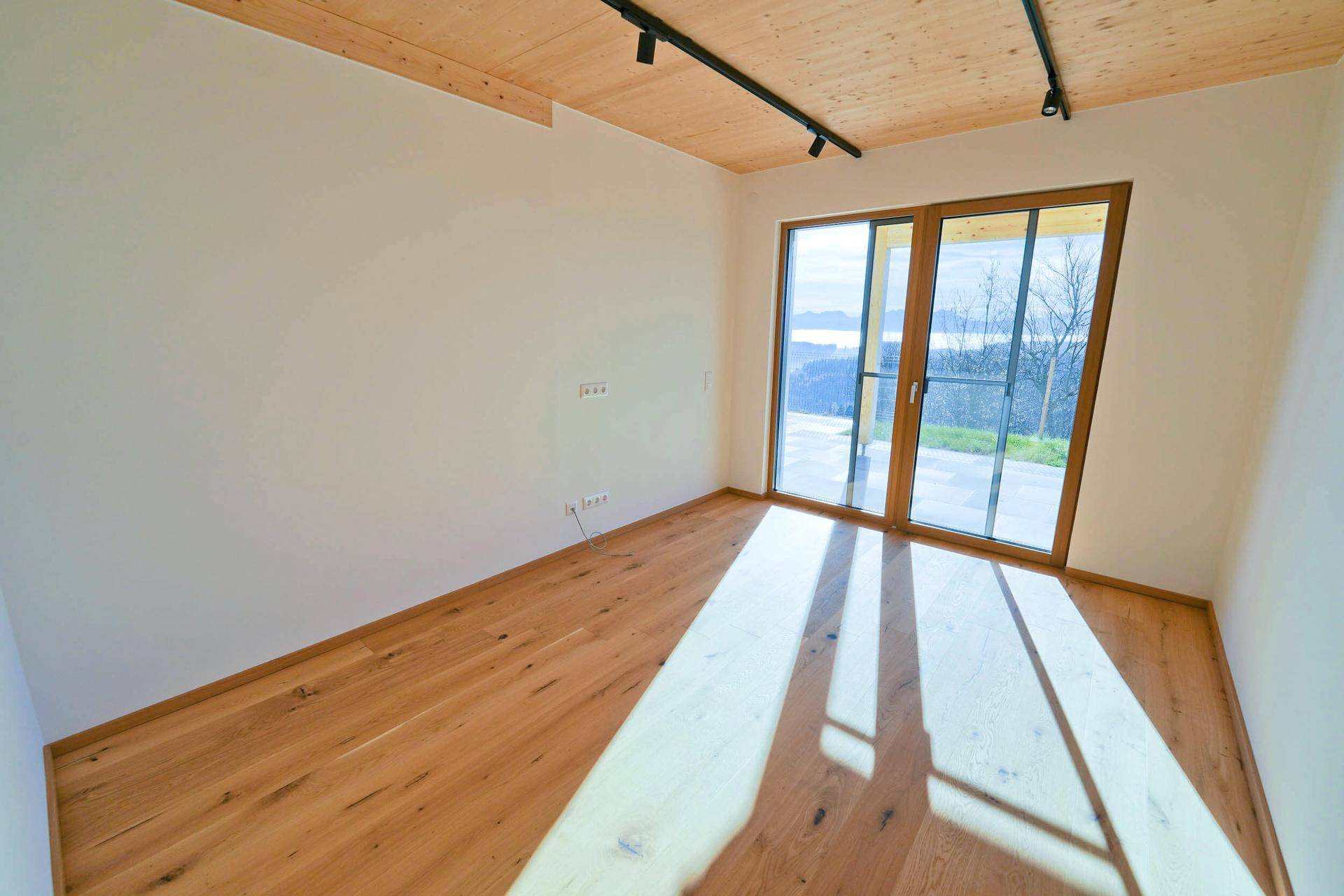 Geräumiges Schlafzimmer mit Holzboden, großen Fenstern und viel natürlichem Licht.