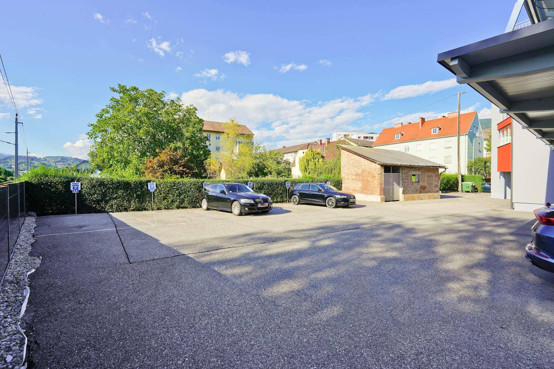 Offener Parkplatzbereich mit mehreren Stellplätzen und einem kleinen Nebengebäude.