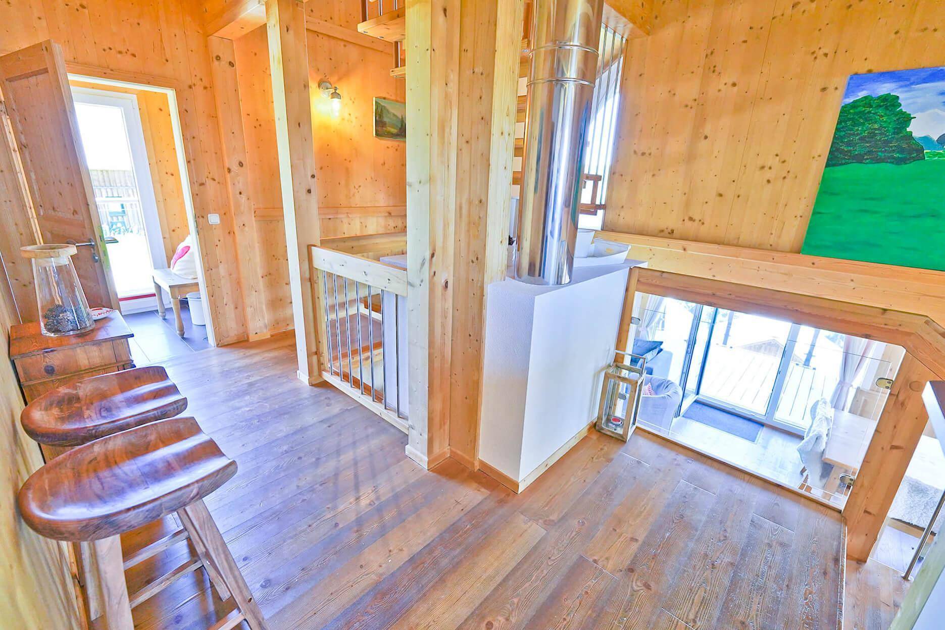 Heller Flur mit Holztreppe, Holzboden und Zugang zu weiteren Räumen.