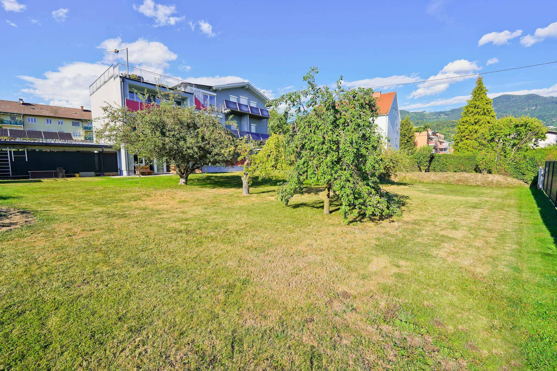 Großer, gepflegter Garten mit Rasenfläche und Obstbäumen hinter dem Wohngebäude.