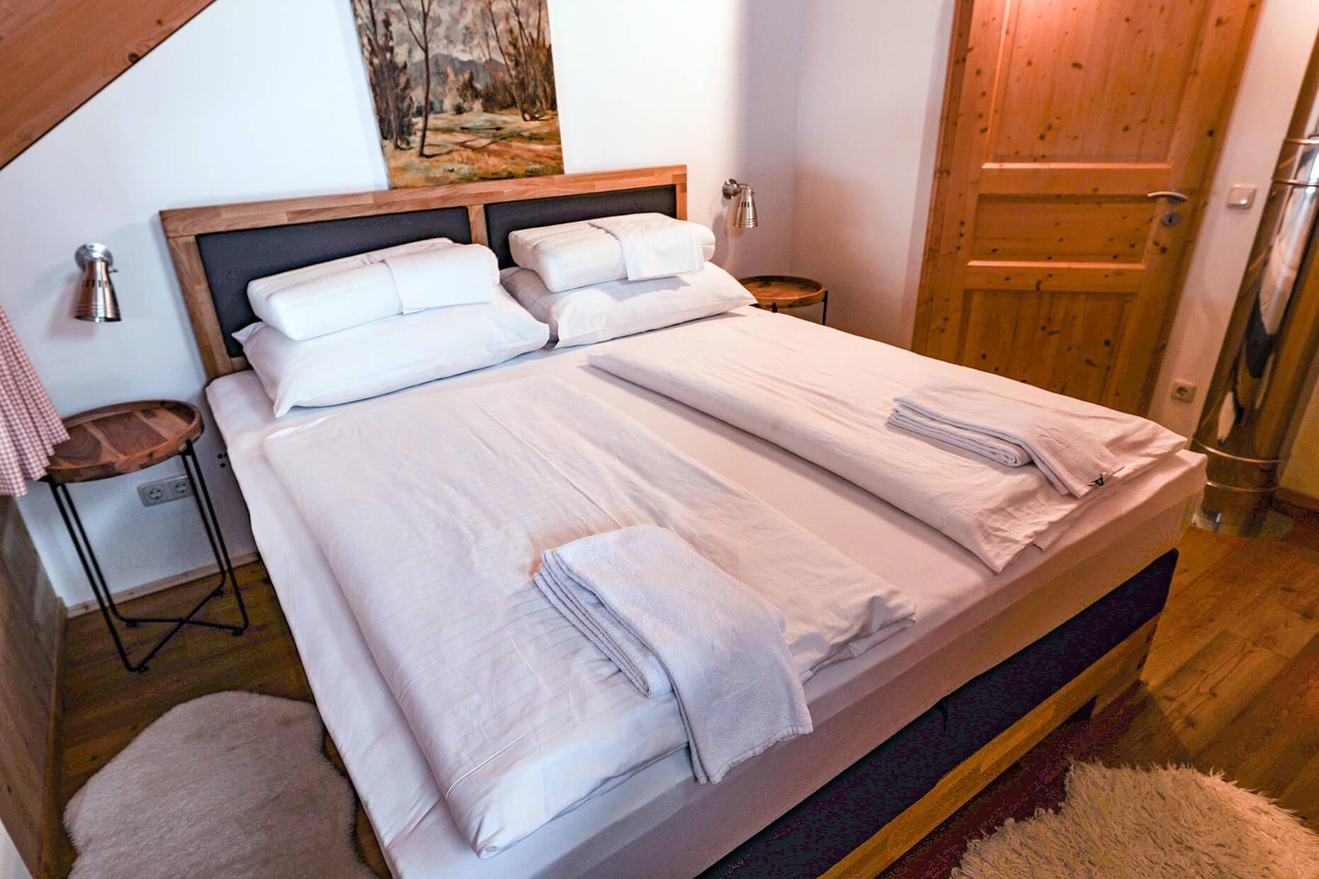 Gemütliches Schlafzimmer im Dachgeschoss mit Doppelbett, Holzwänden und schrägen Decken.