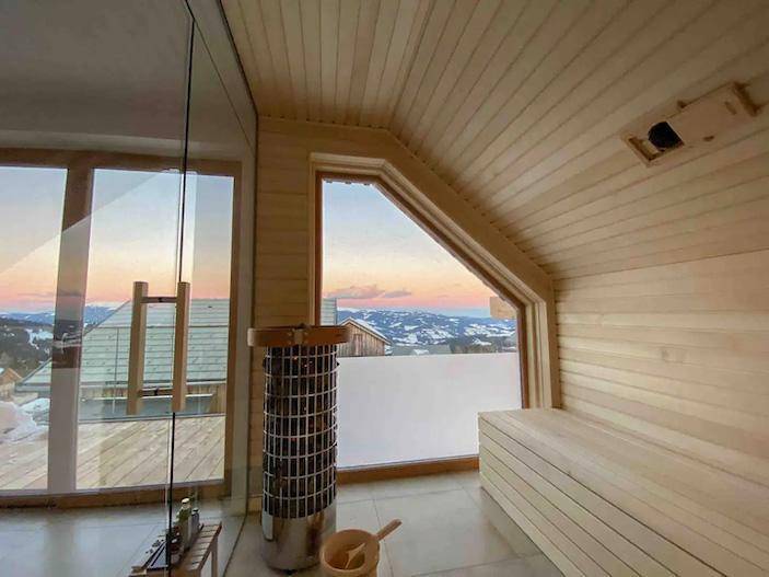 Holzsauna mit Panoramablick auf die verschneite Berglandschaft.