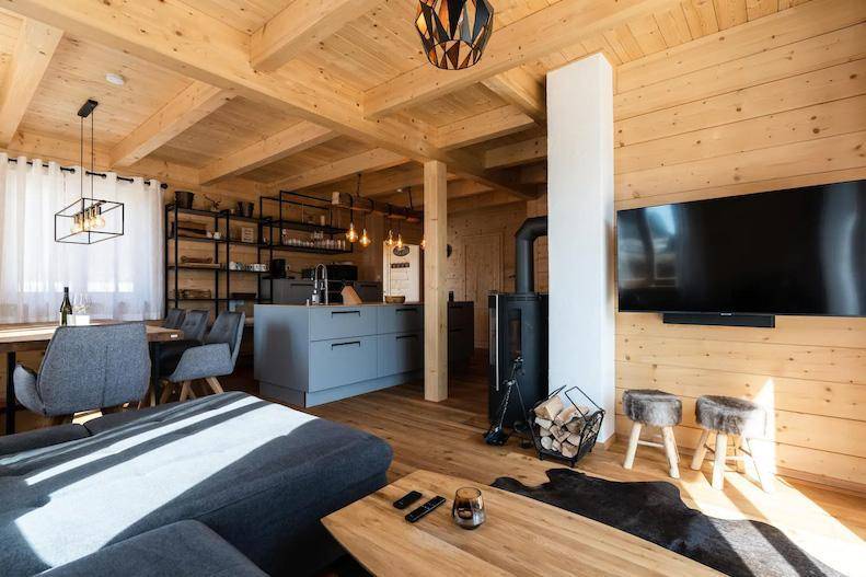 Gemütliches Wohnzimmer mit Sofa, Holzboden und Kaminofen.
